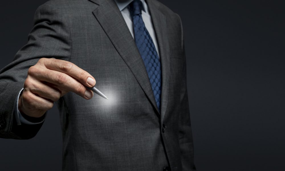 Businessman using a pen and signing on an invisible screen Businessman using a pen and signing on an invisible screen