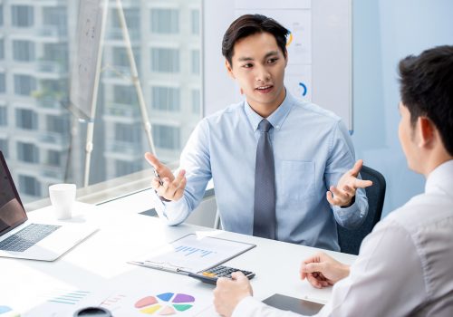 Financial broker explaning business data to his client Attractive Asian financial broker explaning business data to his client during their private meeting in the office